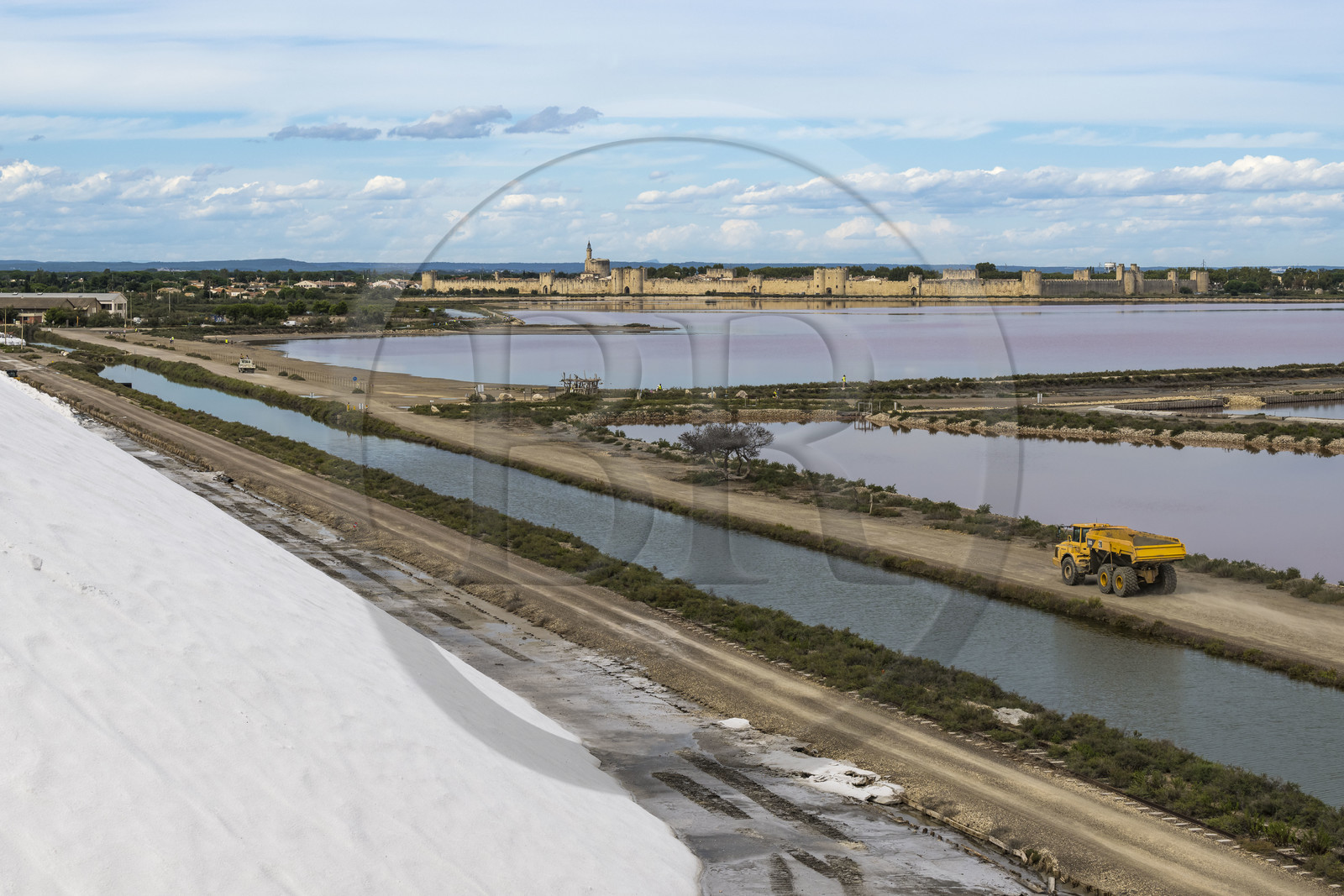 France, Gard (30), Aigues-Mortes, la ville médiévale entourée par ses remparts en bordure des marais salants (Salins du Midi) depuis une montagne de sel stocké