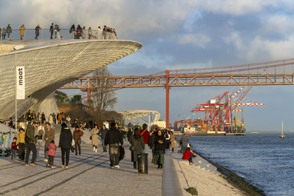 Portugal, Lisbon, Belem district, MAAT (Museum of Art, Architecture and Technology or Museu de Arte, Arquitetura e Tecnologia) on the banks of the Tagus, inaugurated in 2016 and designed by British architect Amanda Levete, the Ponte 25 de Abril bridge and the port of Lisbon in the background