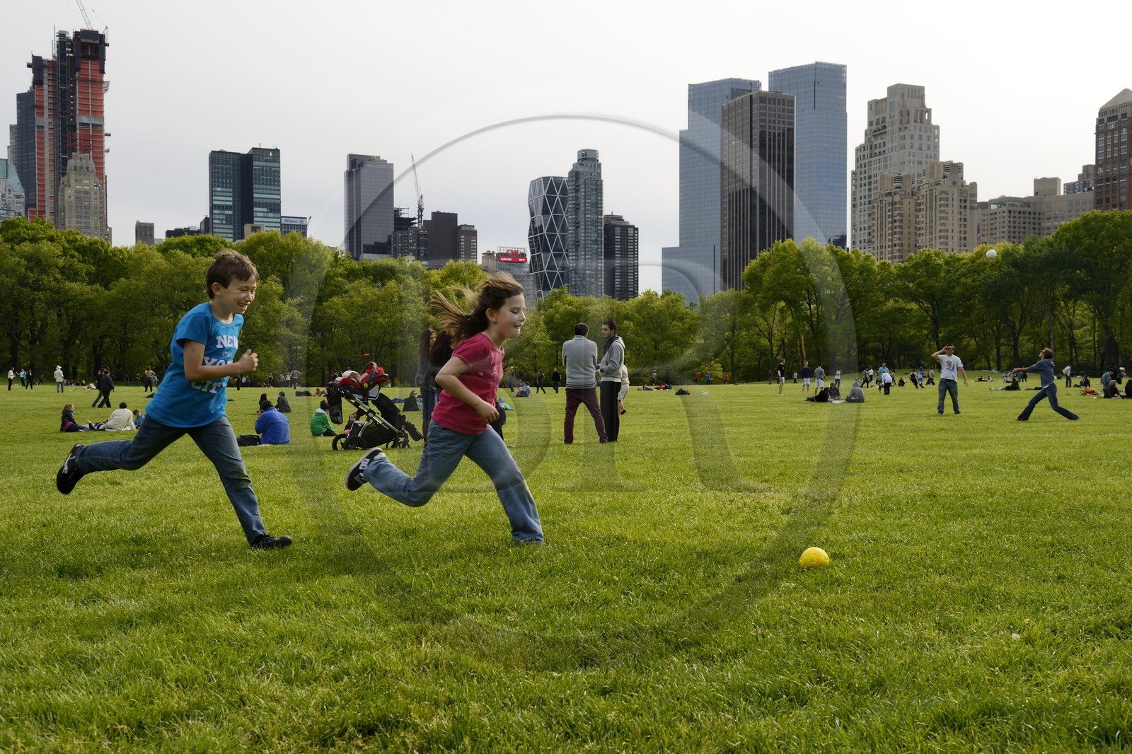 United States, New York City, Manhattan, Central Park, children playing football on the Sheep Meadow, Central Park South buildings in the background