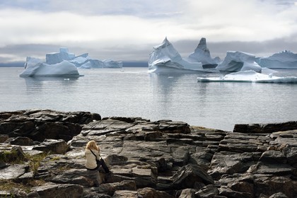 Groenland, cote ouest, Ile de Disko, baie du village de Qeqertarsuaq, randonneur sur les rochers et icebergs en arrière plan