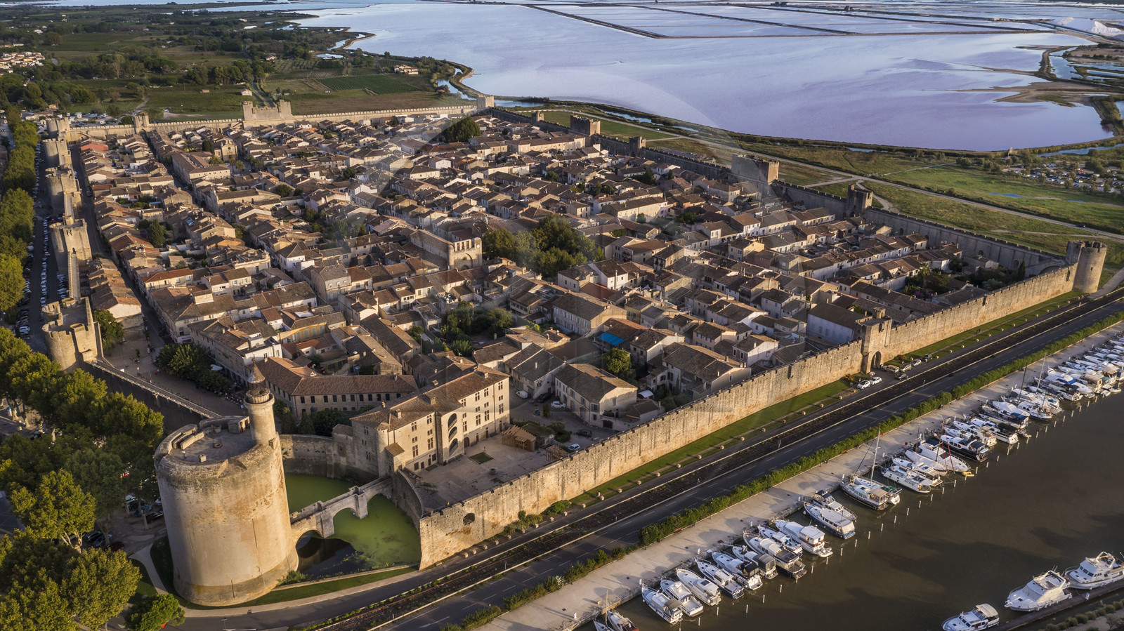 France, Gard (30), Aigues-Mortes, la ville médiévale entourée par ses remparts, la Tour de Constance et le port du canal du Rhône à Sète au premier plan, les marais salants (Salins du Midi) en arrière plan (vue aérienne)