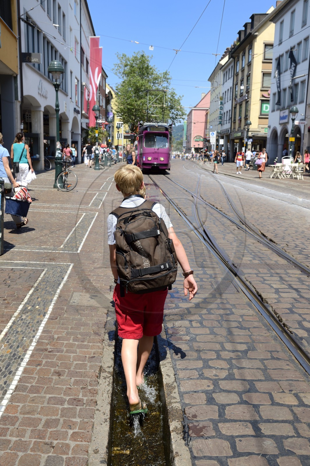 Allemagne, Bade-Wurtemberg, Fribourg en Brisgau, retour d'ecole dans la Kaiser-Joseph Strasse, un des Bächle qui sont des petits caniveaux ouverts qui bordent les trottoirs de la vieille ville