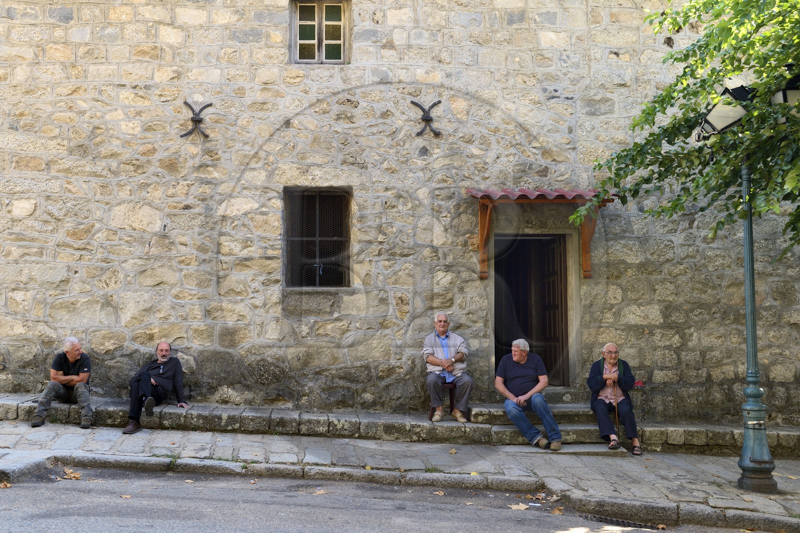 France, Corse-du-Sud (2A), Alta Rocca, Sainte-Lucie-de-Tallano (Santa Lucia di Tallà), hommes en discussion devant l'église du village