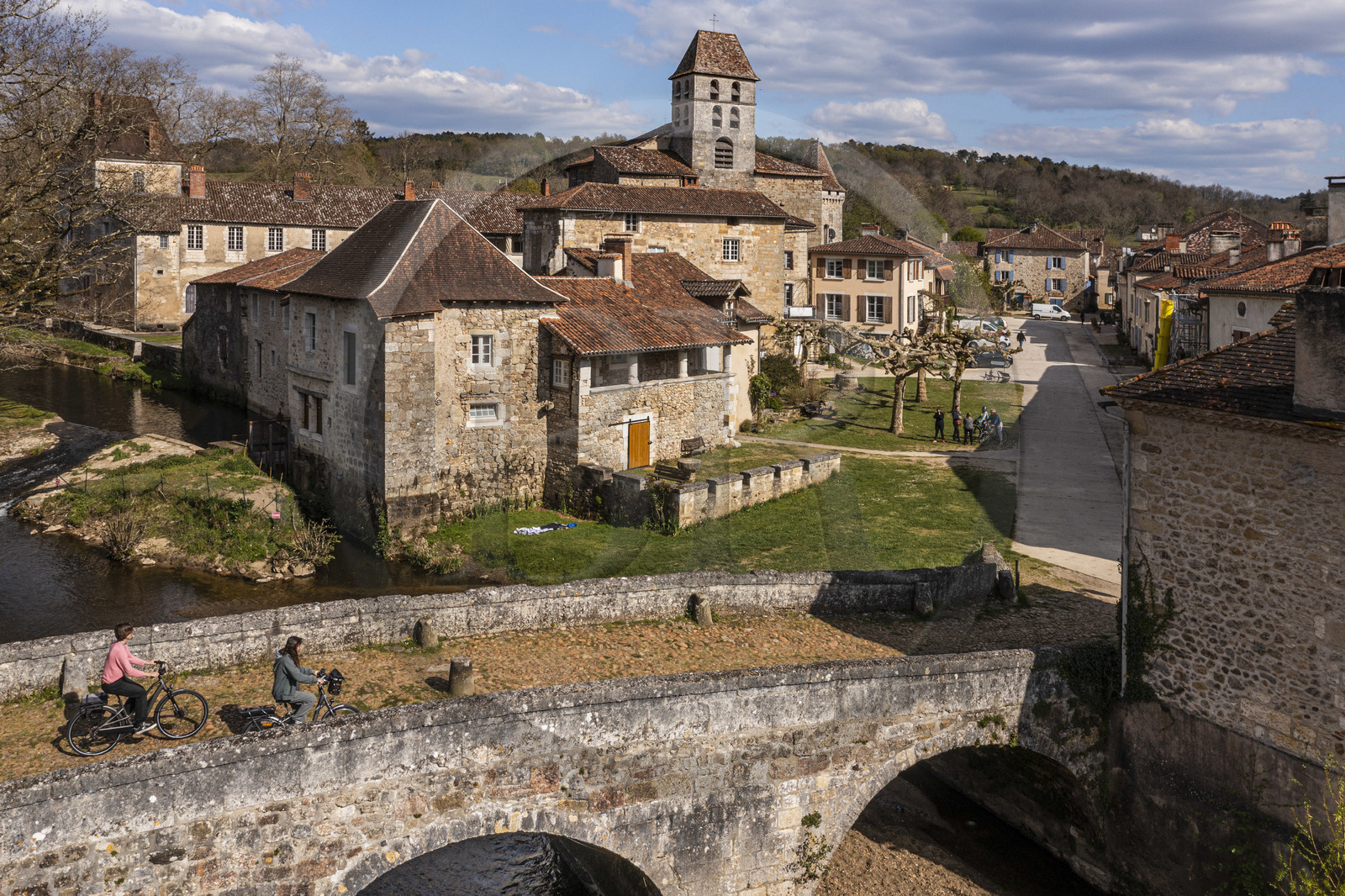 France, Dordogne (24), Périgord Vert, Saint-Jean-de-Côle, labellisé Les Plus Beaux Villages de France, cyclistes faisant la véloroute la Flow Vélo franchissant le pont médiéval du XIIème siècle, le clocher de l'église Saint-Jean-Baptiste (vue aérienne)