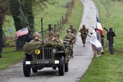 France, Eure, Sainte Colombe prés Vernon, Allied Reconstitution Group (US World War 2 and french Maquis historical reconstruction Association), reenactors in uniform of the 101st US Airborne Division progressing in a jeep Willys welcomed as liberators by villagers and FFI