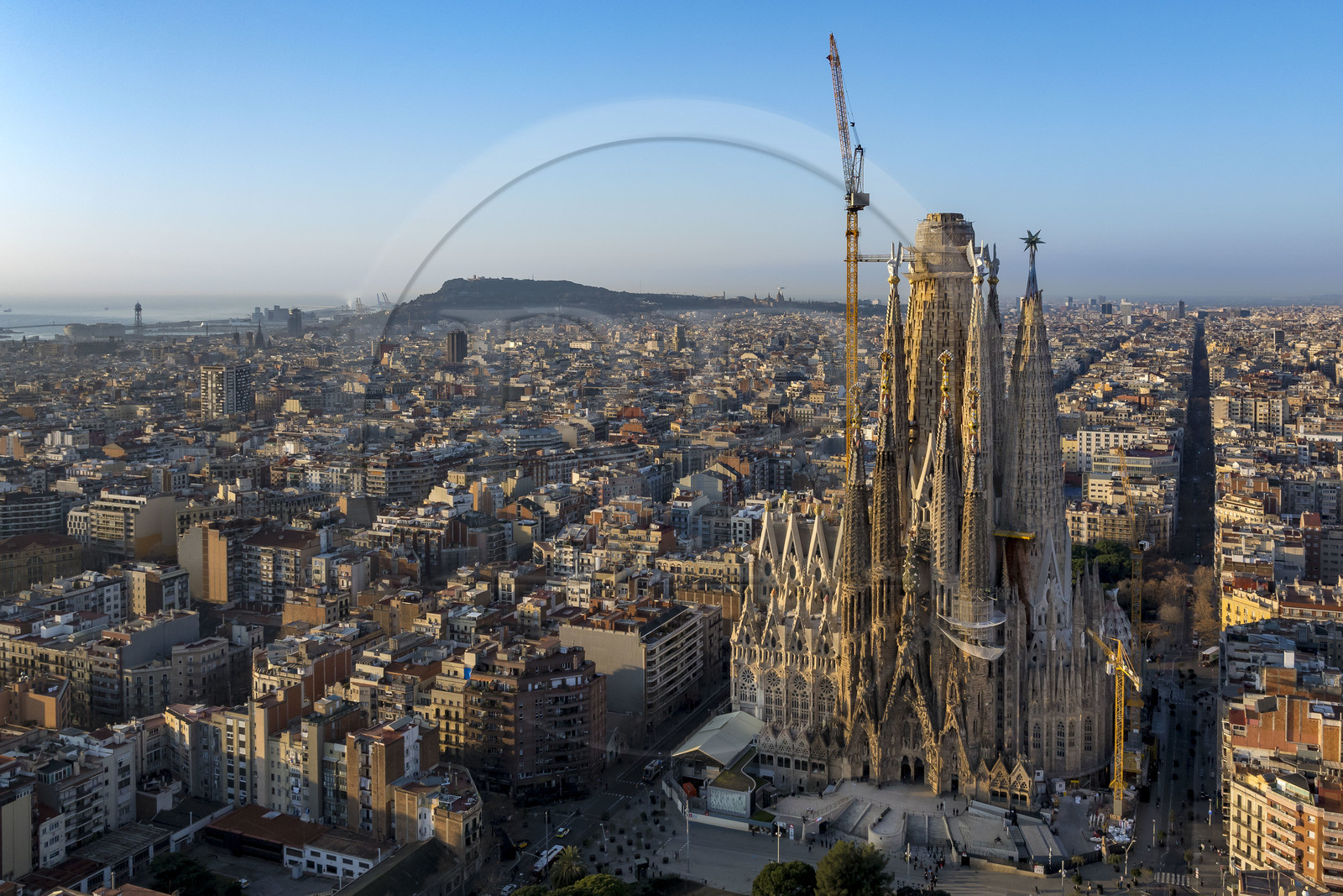 Spain, Catalonia, Barcelona, Eixample district, Sagrada Familia basilica by Catalan modernist architect Antoni Gaudi, listed as a UNESCO World Heritage Site, facade of the Nativity, the port and Montjuic hill in the background