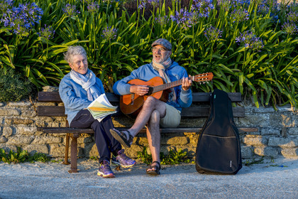 France, Finistère (29), Iles du Ponant, Ile de Batz, Remi joue de la guitare pour Françoise sur un banc de l'embarquadère en fin de journée