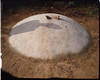 Burkina Faso, province de Poni, pays des Lobi, région de Loropéni, Lakar, tombe d'un enfant par l'ombre de son père, la plupart des tombes comportent un ou plusieurs éléments ayant appartenus au défunt, ici il s'agit des sandales de l'enfant mais le plus souvent on trouve, scellés dans la tombe, la vaisselle du disparu (bol, assiette et même fourchette)