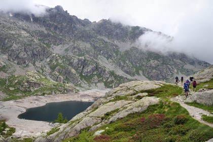 France, Alpes-Maritimes, parc national du Mercantour (Mercantour National Park), Valmasque valley, hikers on the trail over the lac Vert (Green Lake)