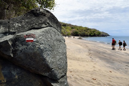 France, Ile de Mayotte, Grande-Terre, M'Tsamoudou, plage de Saziley, randonneurs marchant sur la plage sur le sentier de grande randonnée faisant le tour de l'ile, marque du sentier de randonnée du GR
