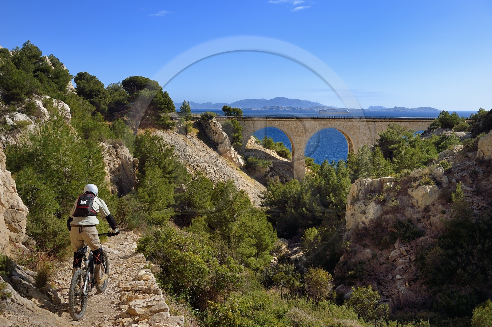 France, Bouches-du-Rhône (13), Le Rove vers Marseille, la Cote Bleue, randonnée de Niolon au Cap Méjean le long du Sentier des Douaniers, vététiste descendant vers le pont ferroviaire de la calanque du Jonquier et l’archipel des Iles du Frioul en arrière plan