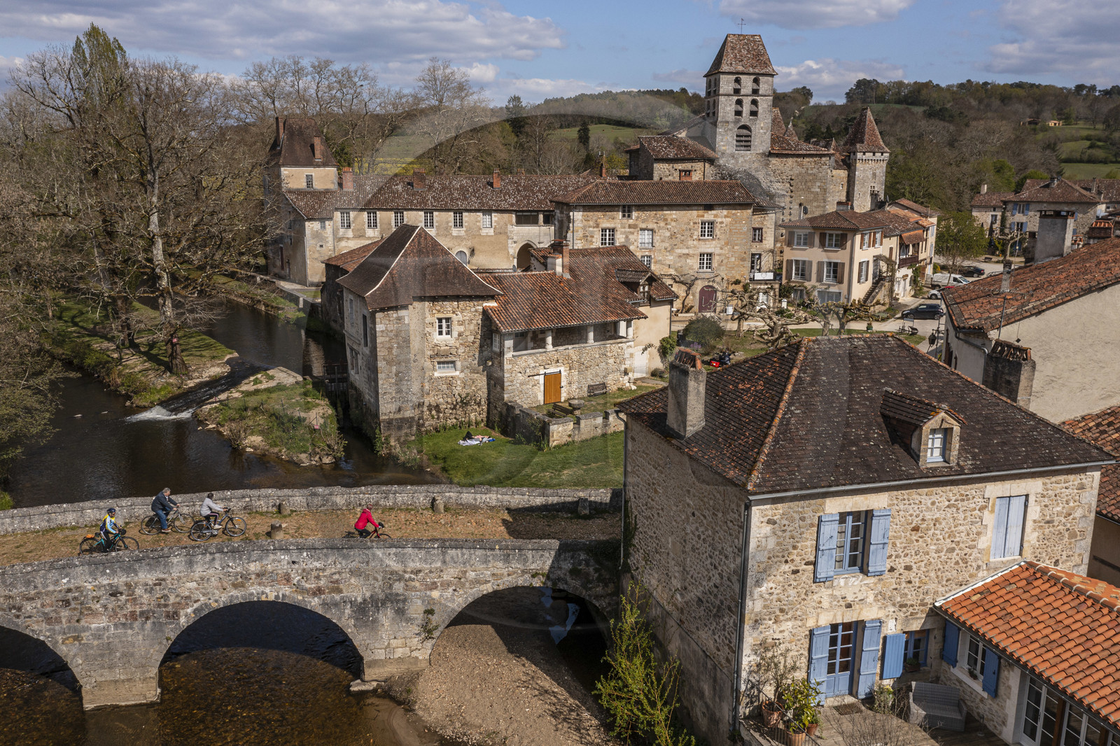 France, Dordogne, Périgord Vert, Saint Jean de Cole, labelled Les Plus Beaux Villages de France (The Most Beautiful Villages of France), cyclists on the Flow Vélo cycle route crossing the medieval bridge of the 12th century, the St. John the Baptist (Saint-Jean-Baptiste) church bell tower (aerial view)