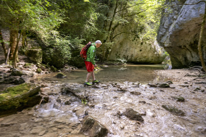 France, Vaucluse, Mont Ventoux Regional Natural Park, Monieux, Gorges de La Nesque, hiker crossing the Nesque river at the ford of the Saint-Michel chapel