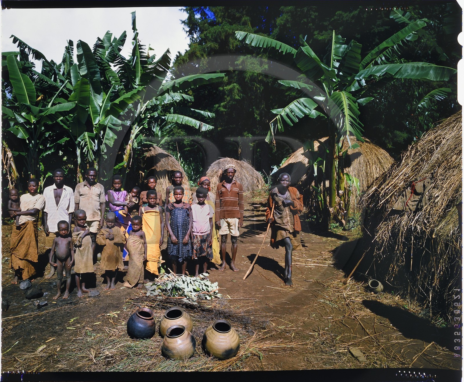 Burundi, province de Muyinga, potiers Twa ou Batwa (pygmées), leur habitat est généralement très pauvre comme ici des cases en paille, les pots (inkono) en argile sont modelés à la main sur un tesson de vieux pot par la technique du colombin, après être lissé, un dessin est imprimé à l'aide d'un bâtonnet ou d'une cordelette tressée qu'on fait rouler sur la surface du pot, lorsque les pots sont secs au bout de plusieurs jours, ils sont sommairement cuits dans un feu de branchages et d'herbes mais les cendres de la cuisson doivent apparaître lors de la vente afin de prouver que le pot n'a jamais été utilisé par les Twa car personne n'en voudrait (reproduction plan-film inversible 4x5)