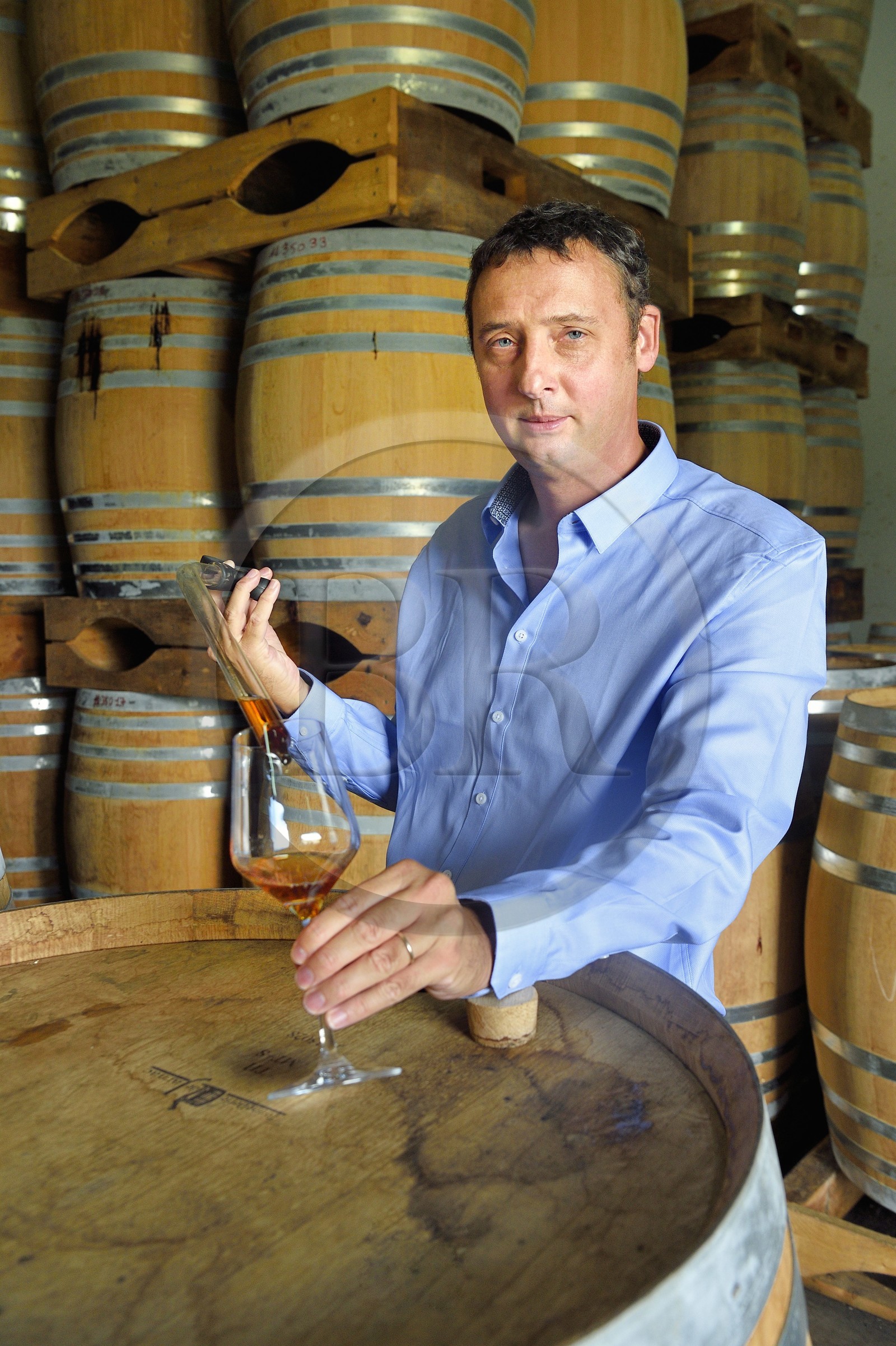 France, Reunion island (French overseas department), Saint Pierre, estate of the Isautier distillery, aging of old rums in the cellars between 6 and 14 months in new barrels then several years afterwards by batch in red barrels, Cyril Isautier director of the rums and punches branch of the Isautier group takes a sample with a pipette for tasting