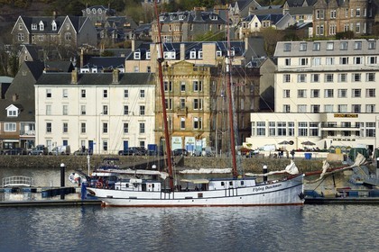 United Kingdom, Scotland, Highland, Argyll and Bute, Flying Dutchman schooner at Oban harbor and the Oban Times in the background