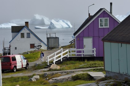 Greenland, west coast, Disko Island, houses in the village of Qeqertarsuaq and icebergs in the background