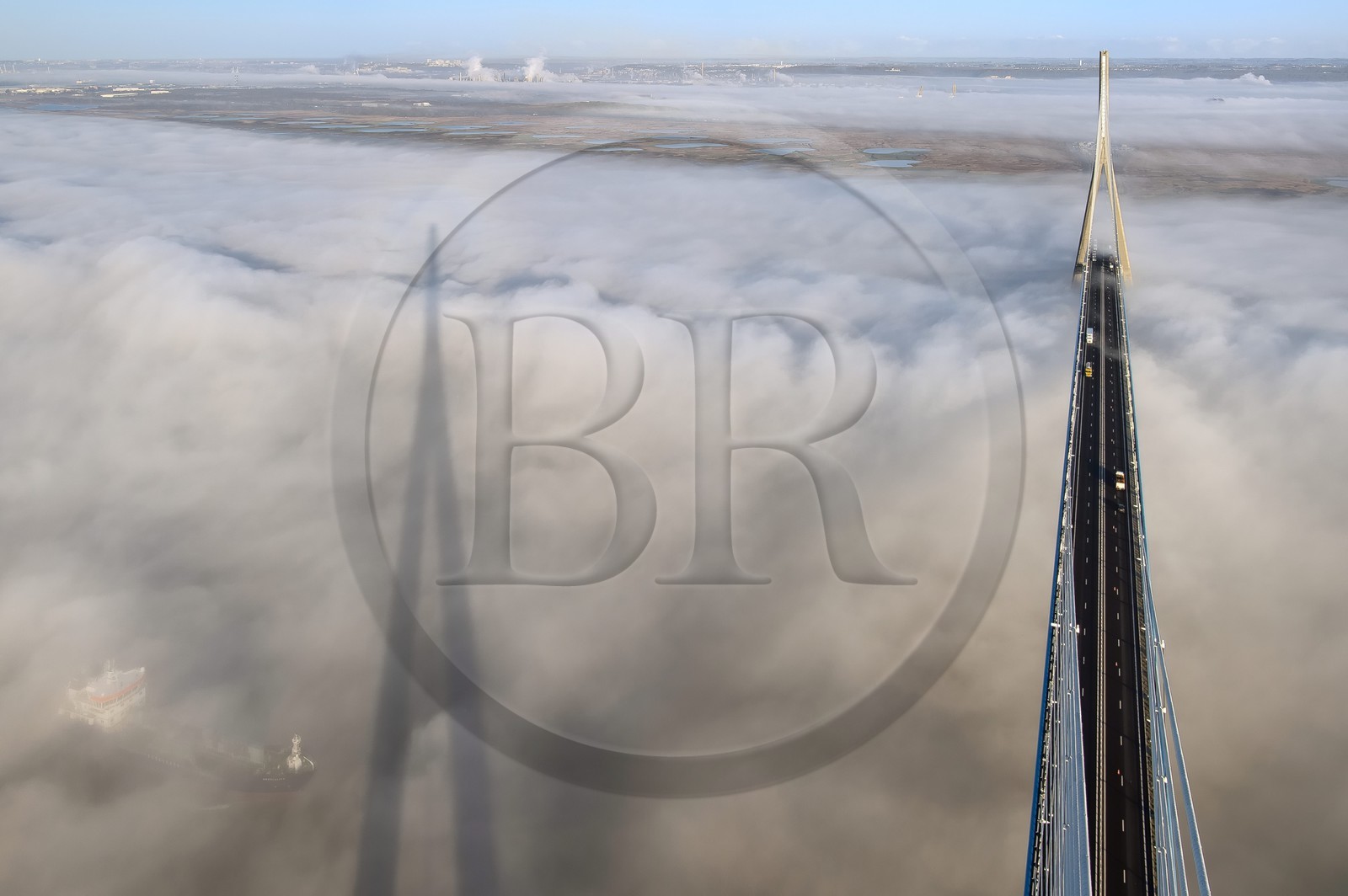 France, entre Calvados (14) et Seine-Maritime (76), cargo passant sous le Pont de Normandie qui émerge des brumes matinales de l'automne et enjambe la Seine, la Réserve Naturelle de l'estuaire de la Seine en arrière plan, vue depuis le sommet du pylone sud