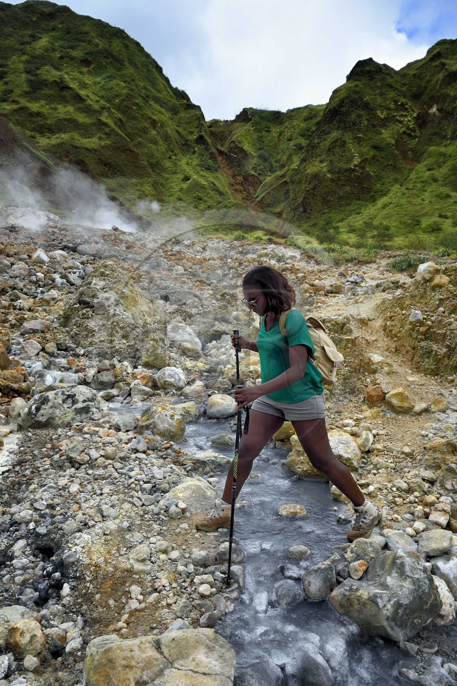 Caraïbes, Ile de la Dominique, Castle Bruce, Parc national du Morne Trois Pitons classé Patrimoine Mondial de l'UNESCO, la Vallée de la Désolation, randonneuse traversant une rivière aux sources d'eau chaude dont la couleur unique est due à la présence de calcium, de carbone, de soufre et de fer, sur le sentier menant au Boiling Lake