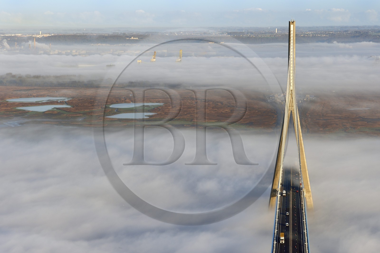 France, entre Calvados (14) et Seine-Maritime (76), le Pont de Normandie enjambe la Seine et émerge d'une mer de nuages, la Réserve Naturelle de l'estuaire de la Seine en arrière plan