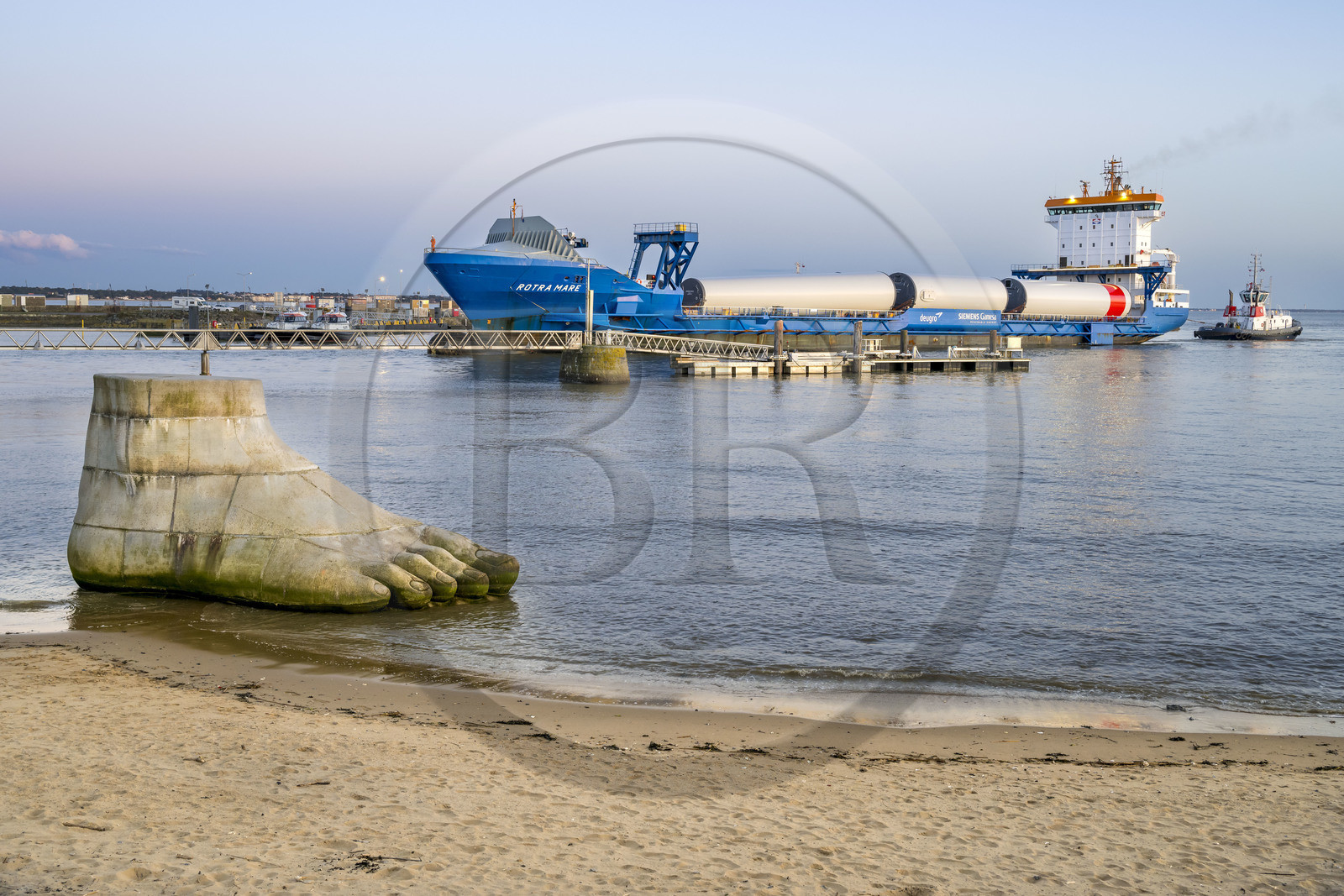 France, Loire-Atlantique (44), Estuaire de la Loire, Saint-Nazaire, collection d'art contemporain à ciel ouvert Estuaire, une des trois sculptures monumentales en béton Le pied, le pull et le système digestif réalisée par les artistes Daniel Bewar et Gregory Gicquel en bordure du Quai de la Jetée, le General Cargo Rotra Mare transportant des sections des mats d'éoliennes en arrière plan