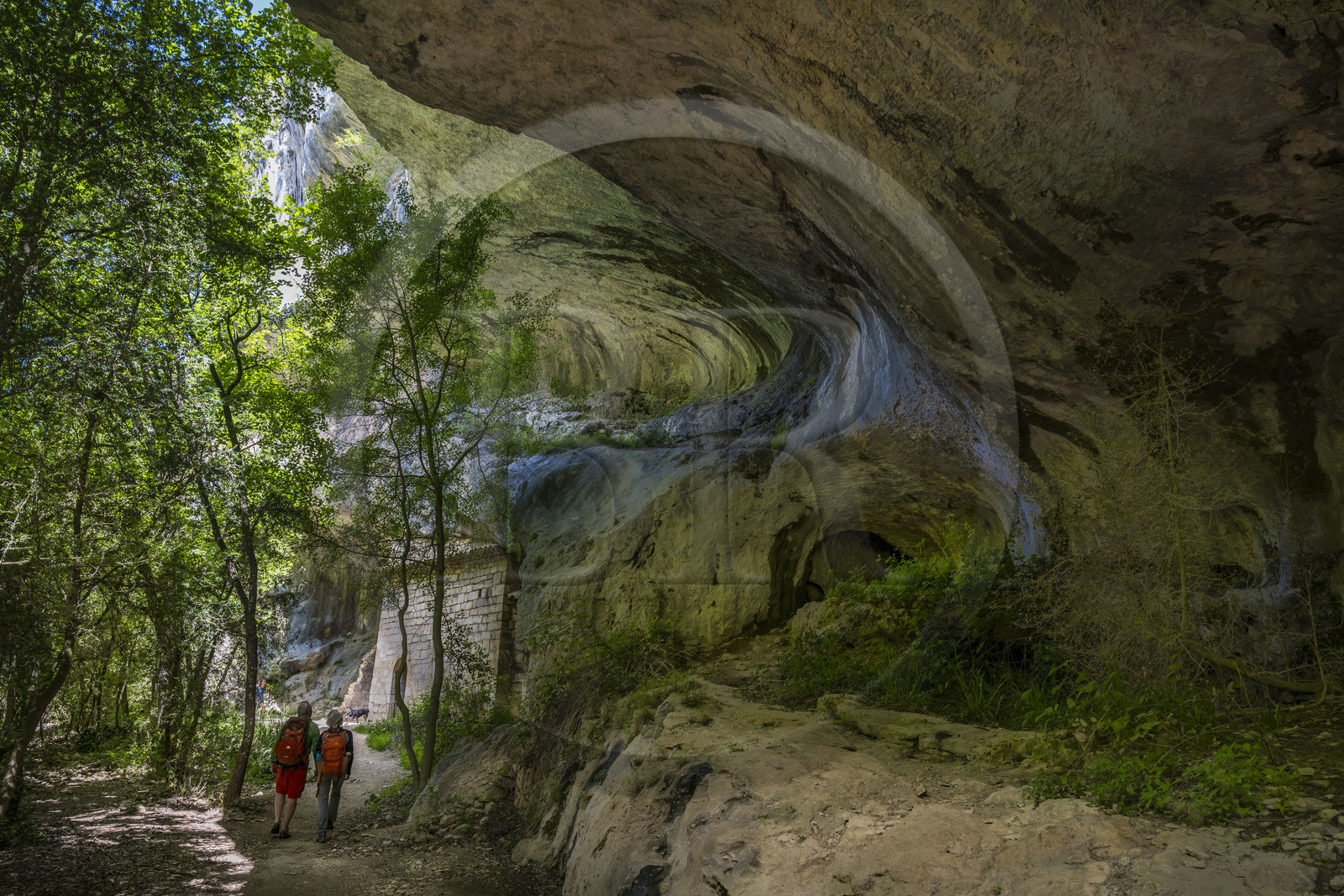 France, Vaucluse (84), Parc naturel régional du Mont Ventoux, Monieux, Gorges de La Nesque, randonneurs marchand sous une barre rocheuse au fond du canyon vers la chapelle Saint-Michel du XIIe siècle