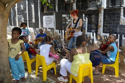 South Africa, Gauteng Province, Johannesburg, CBD (Central Business District), Maboneng district, Sidewalk Sessions in Fox street, Kelly Grevler gives free guitar lessons for young children in the street