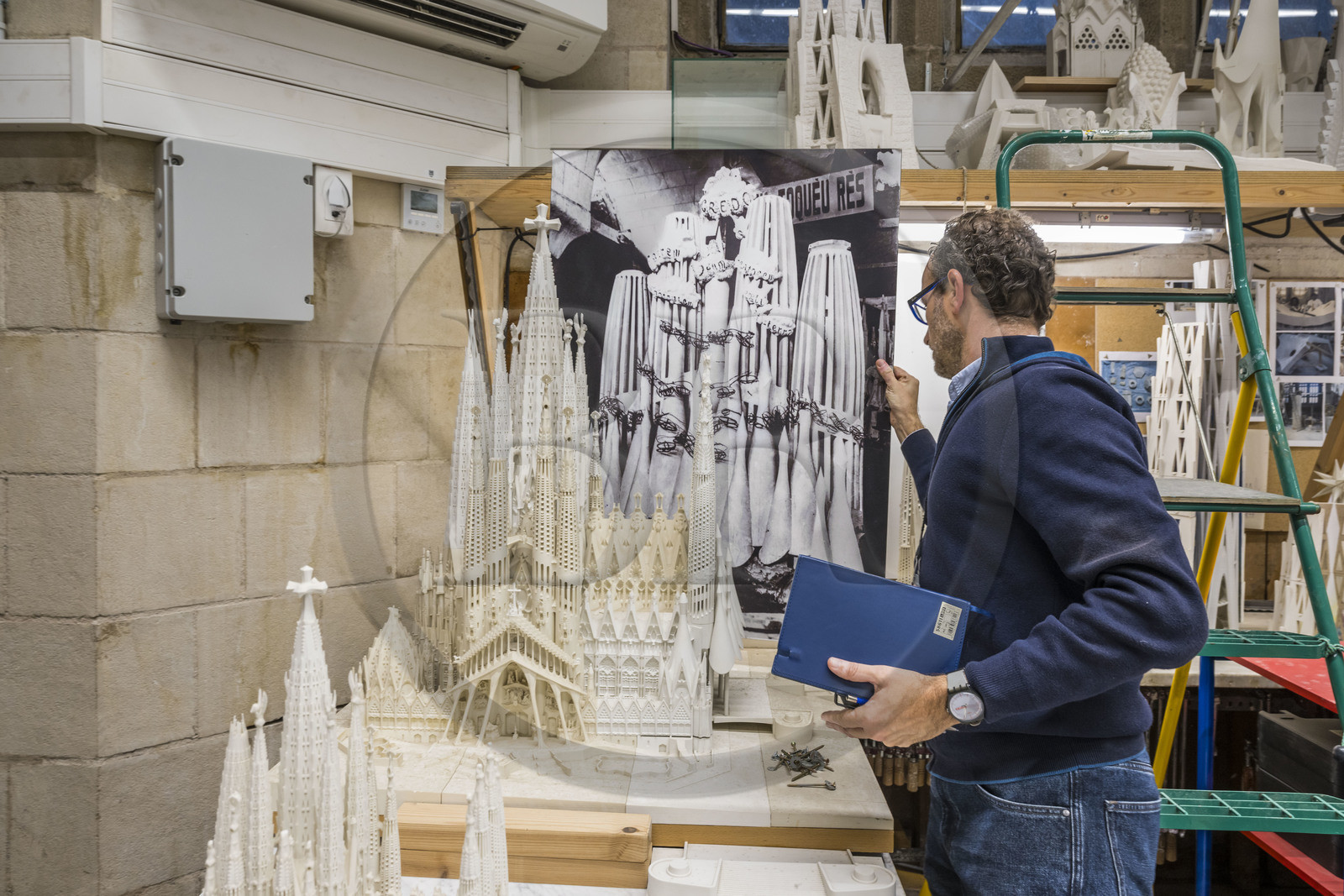Spain, Catalonia, Barcelona, Eixample district, Sagrada Familia basilica by Catalan modernist architect Antoni Gaudi, listed as a UNESCO World Heritage Site, the model workshop, Architect and coordinator of the team of artists and model makers Jeronimo Buxareu Padros presents the next works to be undertaken, the future Glory facade in front of him and the photo of the original Gaudi model in the background