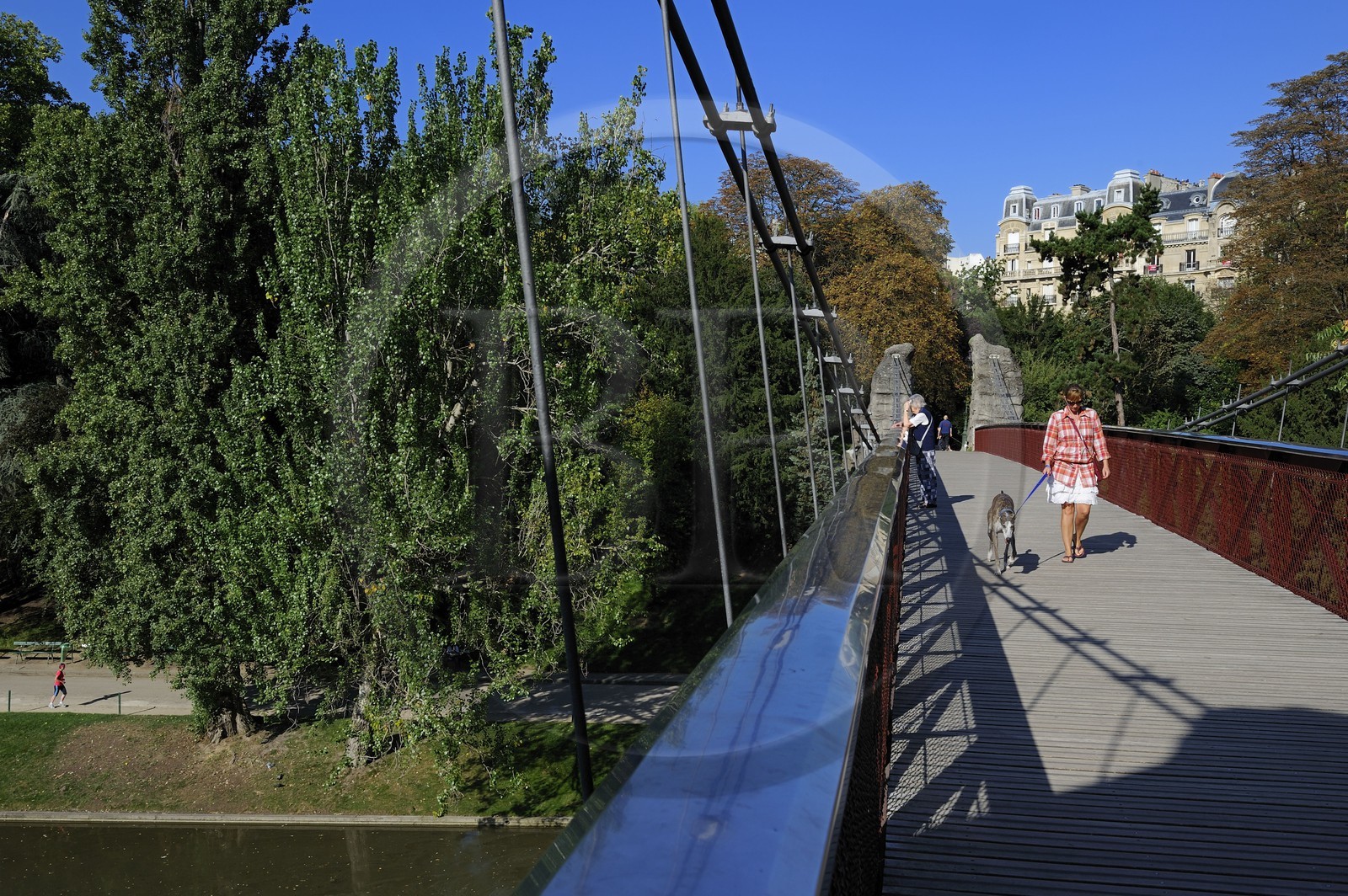 France, Paris (75), parc des Buttes Chaumont, la passerelle suspendue et les immeubles haussmanniens de la rue Manin