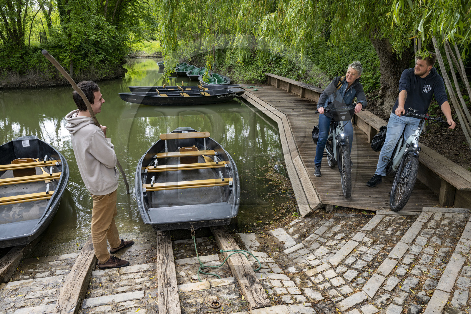 France, Vendée (85), Maillezais, cycliste en discussion avec un batelier tenant sa pigouille (perche en bois) au Grand Port, embarcadère de l'Abbaye