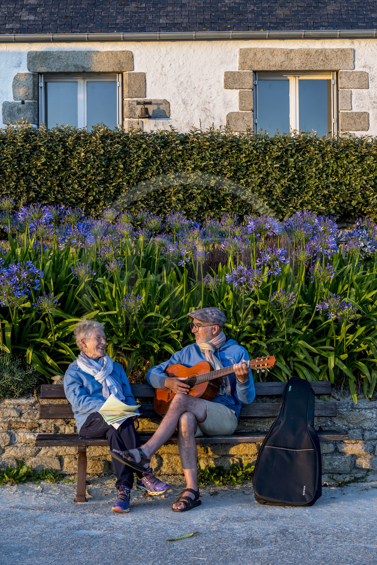 France, Finistère (29), Iles du Ponant, Ile de Batz, Remi joue de la guitare pour Françoise sur un banc de l'embarquadère en fin de journée