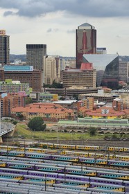 South Africa, Gauteng Province, Johannesburg, colorfull train carriages at Park Station and Johannesburg CBD in the background seen from the district of Braamfontein