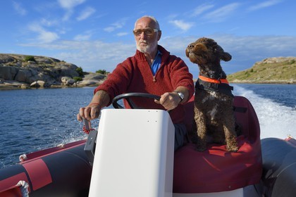 Sweden, Västra Götaland, Smögen, Cyril and his dog Simpson aboard his zodiac