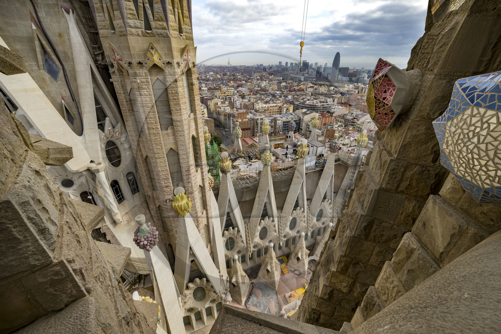 Espagne, Catalogne, Barcelone, quartier de l'Eixample, basilique de la Sagrada Familia de l'architecte du modernisme catalan Antoni Gaudi classée Patrimoine Mondial de l'UNESCO, sommets surmontés de mosaïques en forme de fruits entourant le chantier sur le toit de la nef à l'arrière de la future facade de la Gloire, la Torre Agbar de l'architecte Jean Nouvel en arrière plan