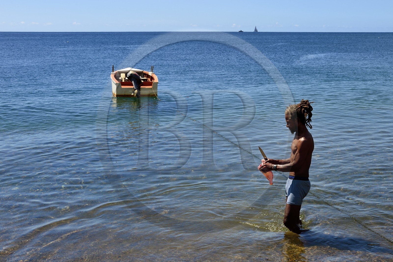 Caraïbes, Ile de la Dominique, baie de Soufrière, un pêcheur nettoie son poisson sur la plage de Soufrière