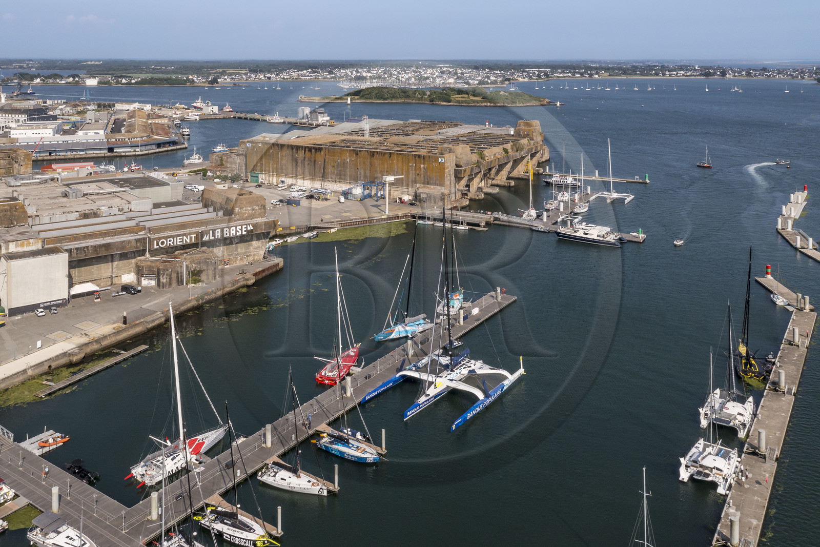 France, Morbihan (56), Lorient, le port de Lorient La Base dans l'ancienne base de sous-marins construite par les Allemands, il est conçu et équipé de façon à accueillir les professionnels du nautisme, les événements nautiques et les grandes unités telles que les monocoques et les multicoques de la Course au Large, voilier maxi-trimaran-hydroptère Maxi Banque populaire XI du navigateur Armel Le Cléac'h (vue aérienne)