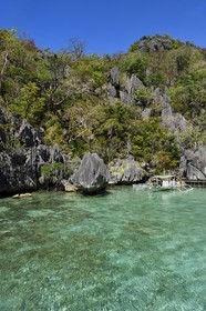 Philippines, Calamian Islands in northern Palawan, Coron Island Natural Biotic Area, Outrigger canoe under limestone rocks