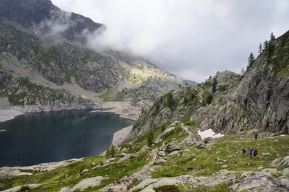 France, Alpes-Maritimes (06), parc national du Mercantour, vallée de la Valmasque, randonneurs sur le sentier de randonnée au dessus du lac Vert et le refuge de la Valmasque (FFCAM) à 2233m en arrière plan