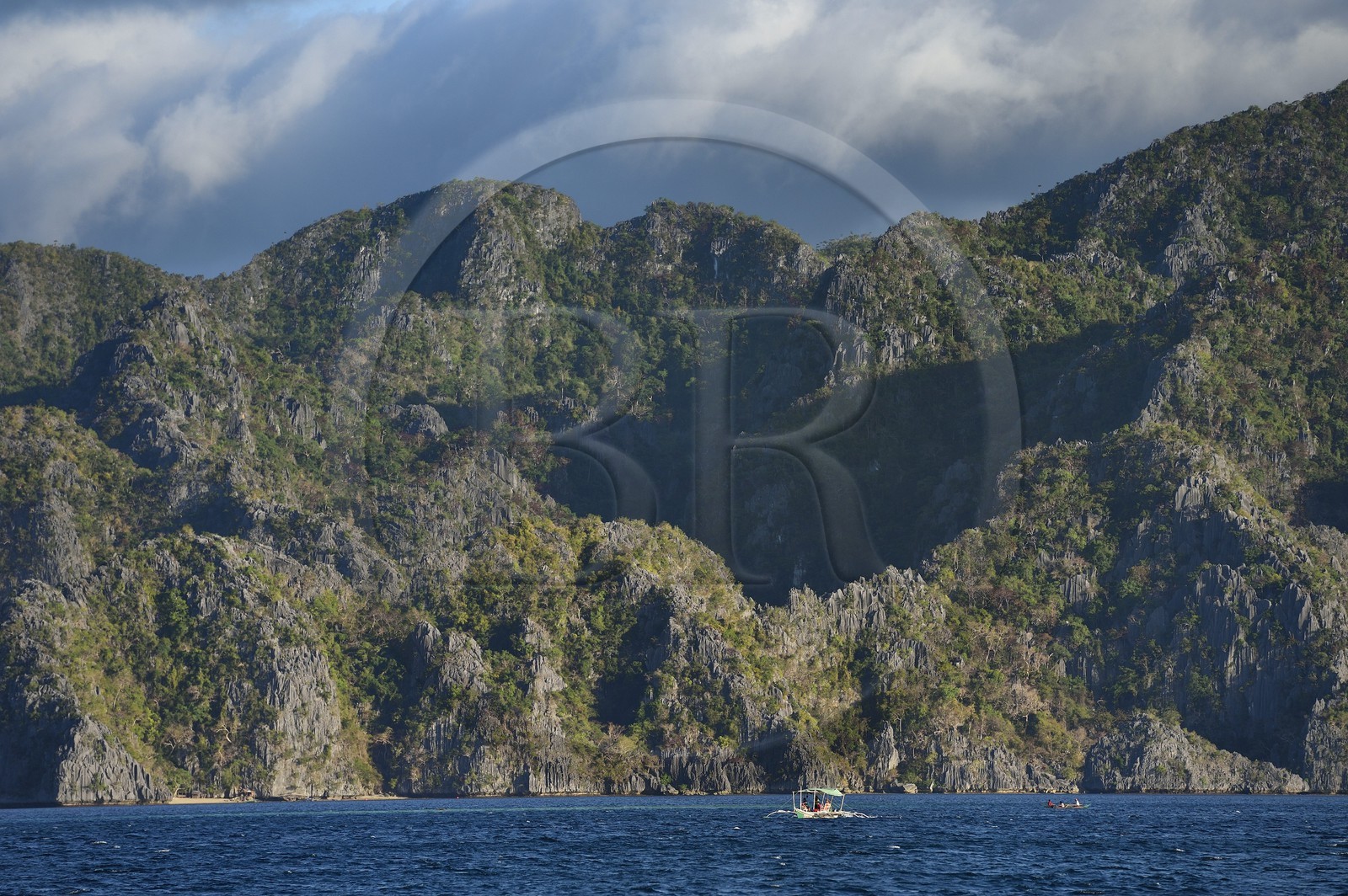 Philippines, Calamian Islands dans le nord de Palawan, Coron Island Natural Biotic Area, pirogue à balancier au pied des murs géants des falaises de calcaire du Permien d'origine jurassique
