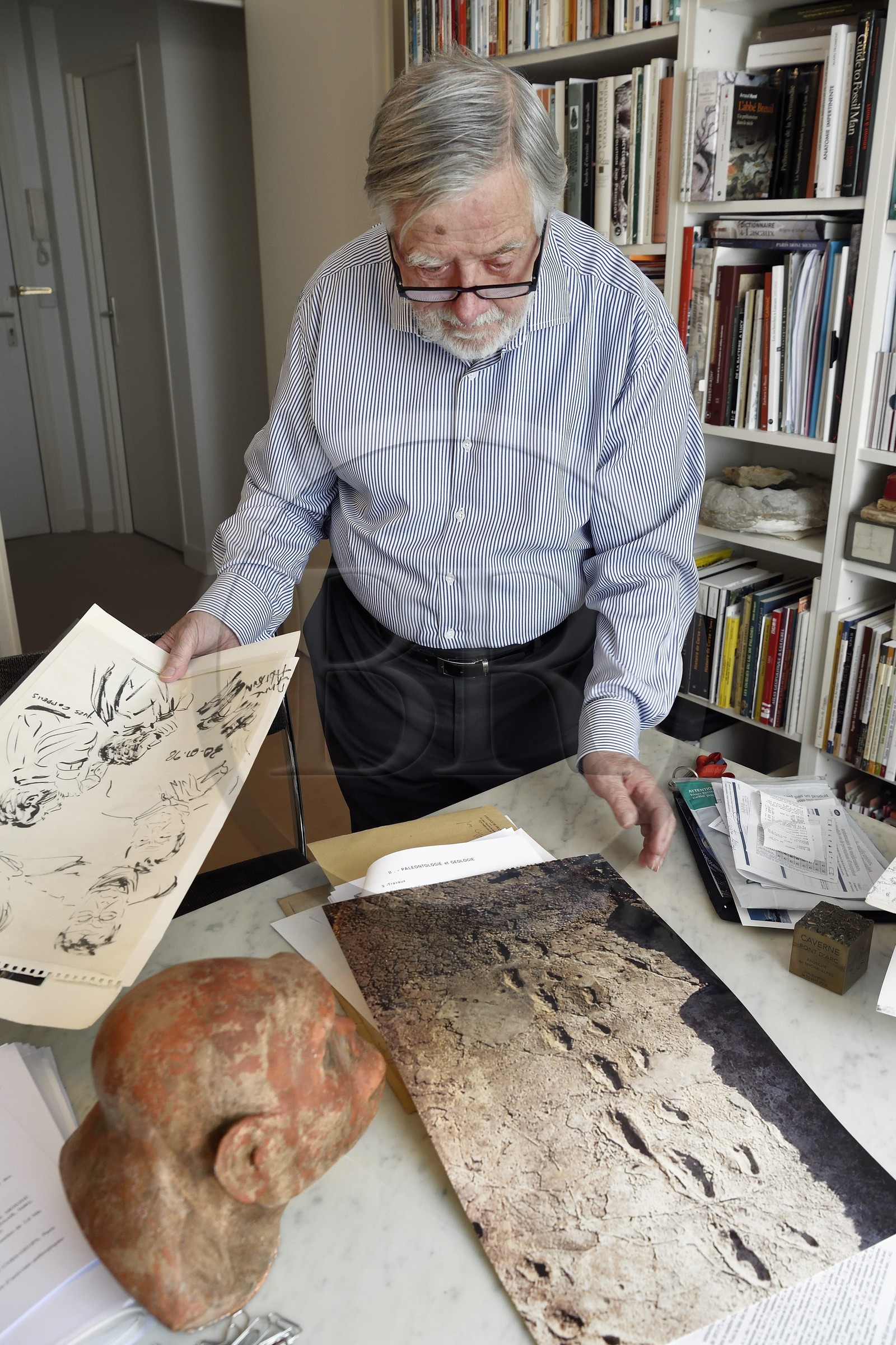 France, Paris, the french paleontologist and paleoanthropologist Yves Coppens, professor at the College de France, in the office of his home in Paris, he shows us a picture of Laetoli footprints under the watch of the supposed reproduction of Lucy's face