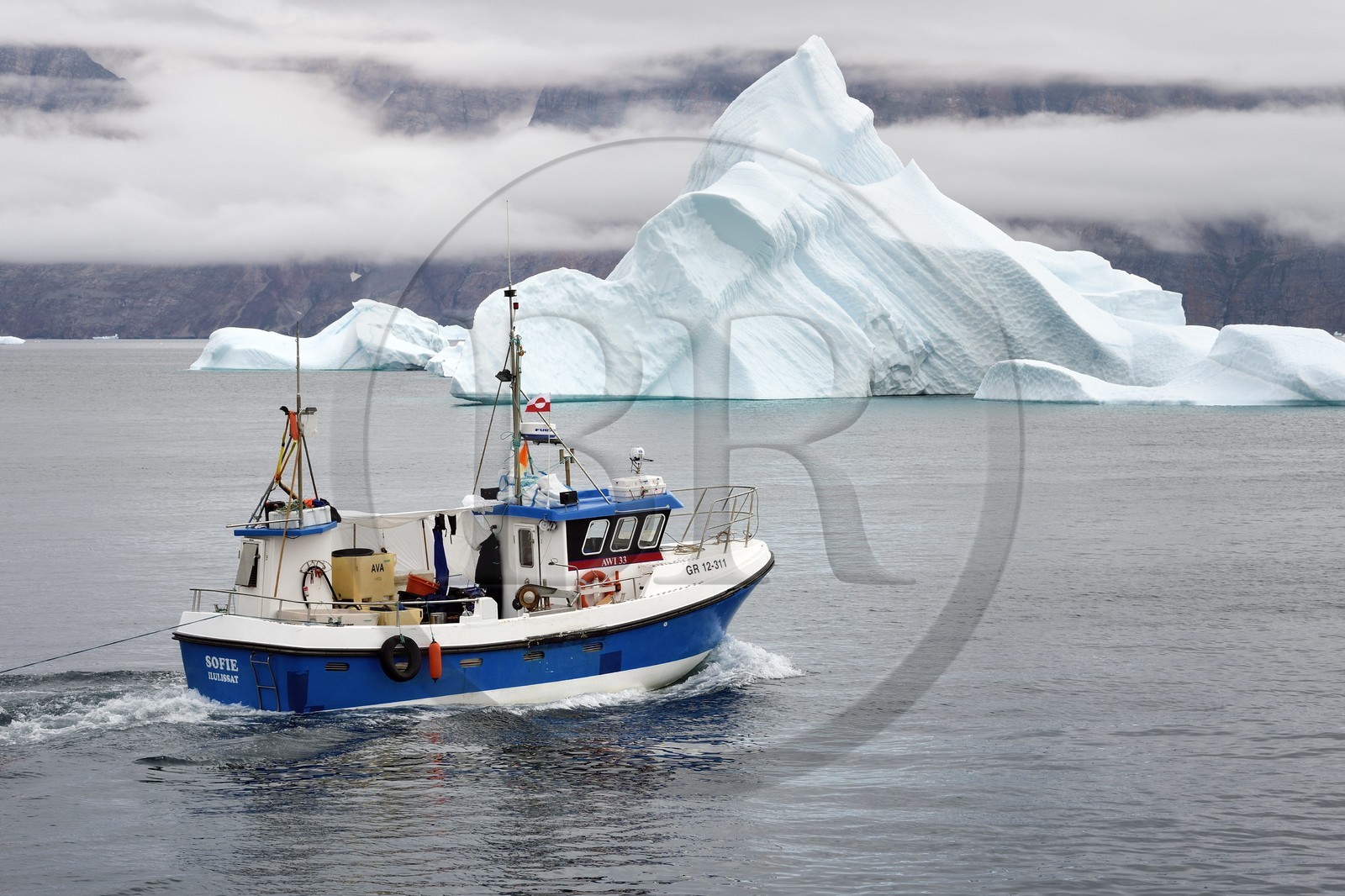 Groenland, cote ouest, Uummannaq, bateau de pêche sortant du port et icebergs en arrière plan