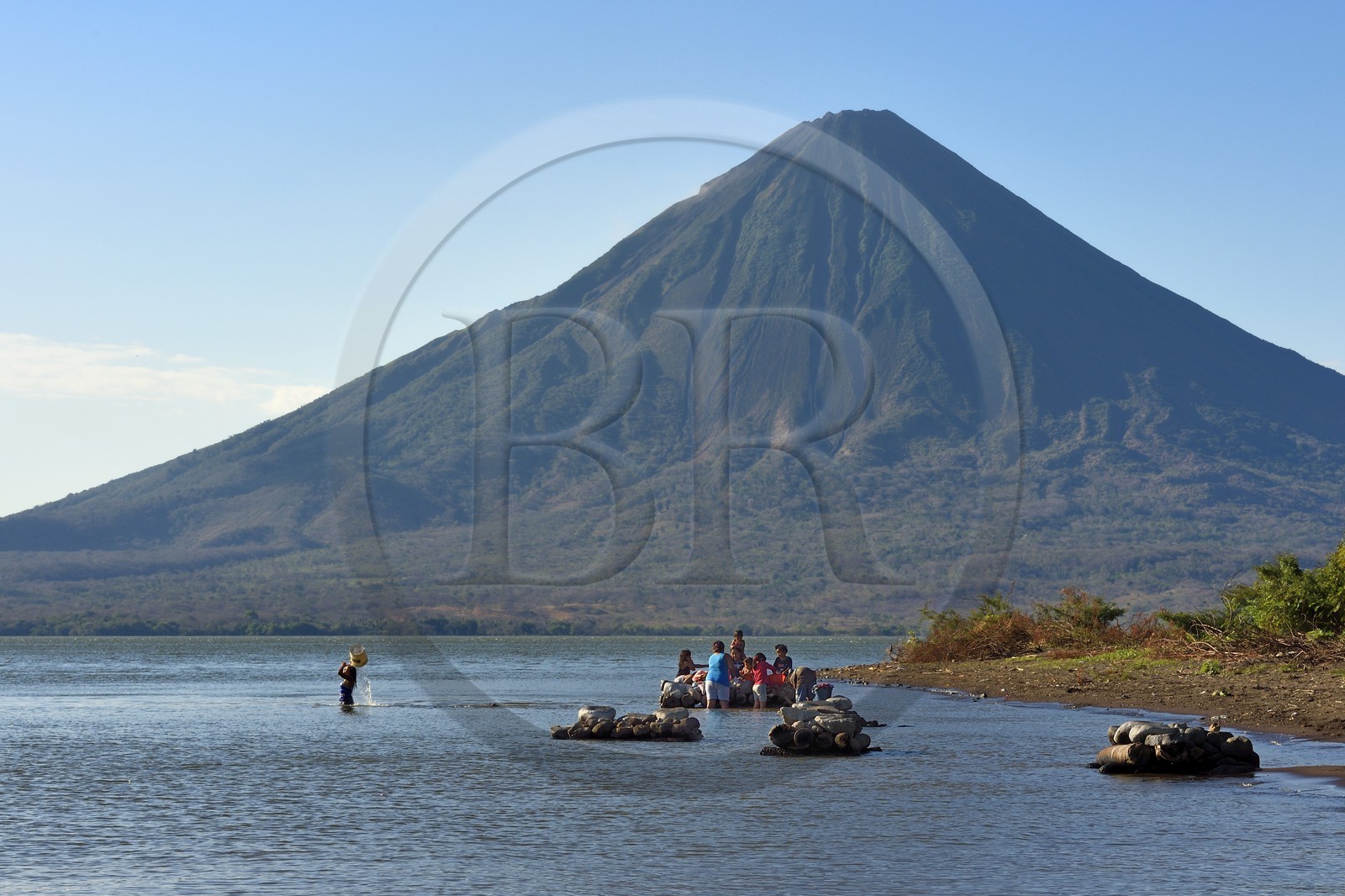 Nicaragua, Ometepe Island in Lake Nicaragua, village of Merida, woman doing her laundry in the lake and the Conception volcano (1610 m) in the background