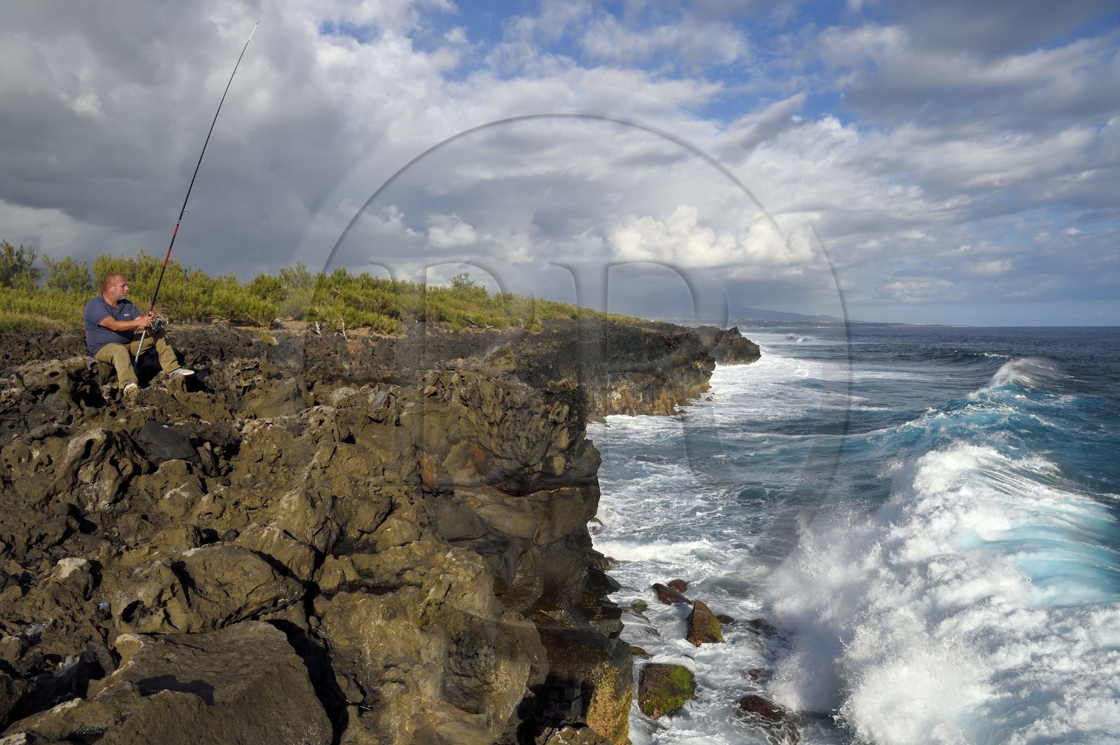 France, Ile de la Reunion, L'Etang Salé les Bains, la côte entre Le Gouffre et l'Etang du Gol, roches noires basaltiques d'origine volcanique tourmentées par l'océan, pêcheur à la ligne
