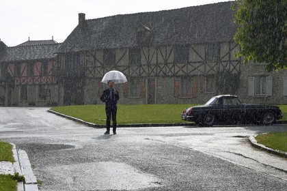 France, Yvelines (78), Montchauvet, tournage pour la télévision du Village Préféré des Français avec Stéphane Bern, Stéphane Bern sous la pluie sur la place de l'église