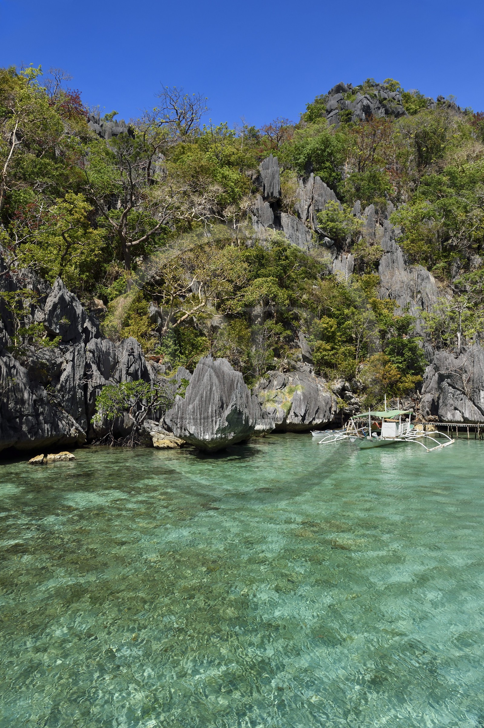 Philippines, Calamian Islands in northern Palawan, Coron Island Natural Biotic Area, Outrigger canoe under limestone rocks