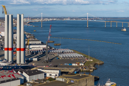 France, Loire-Atlantique (44), Saint-Nazaire, les tours d'éoliennes sont stockées avant embarquement, le pont de Saint-Nazaire en arrière plan (vue aérienne)