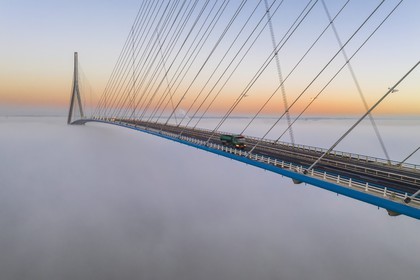 France, entre Calvados (14) et Seine-Maritime (76), le Pont de Normandie émerge des brumes matinales de l'automne et enjambe la Seine pour relier les villes de Honfleur et du Havre