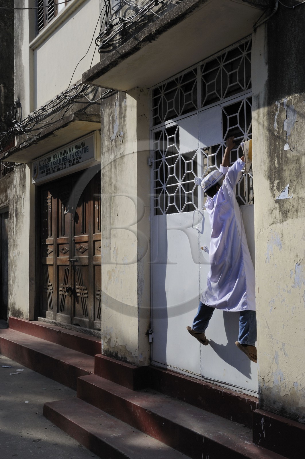 Tanzanie, archipel de Zanzibar, île de Unguja (Zanzibar), ville de Zanzibar, quartier Stone Town, classé Patrimoine Mondial de l' UNESCO, une ruelle de la vieille ville dans le quartier de Shangani, enfant tentant d'accéder à la sonnette