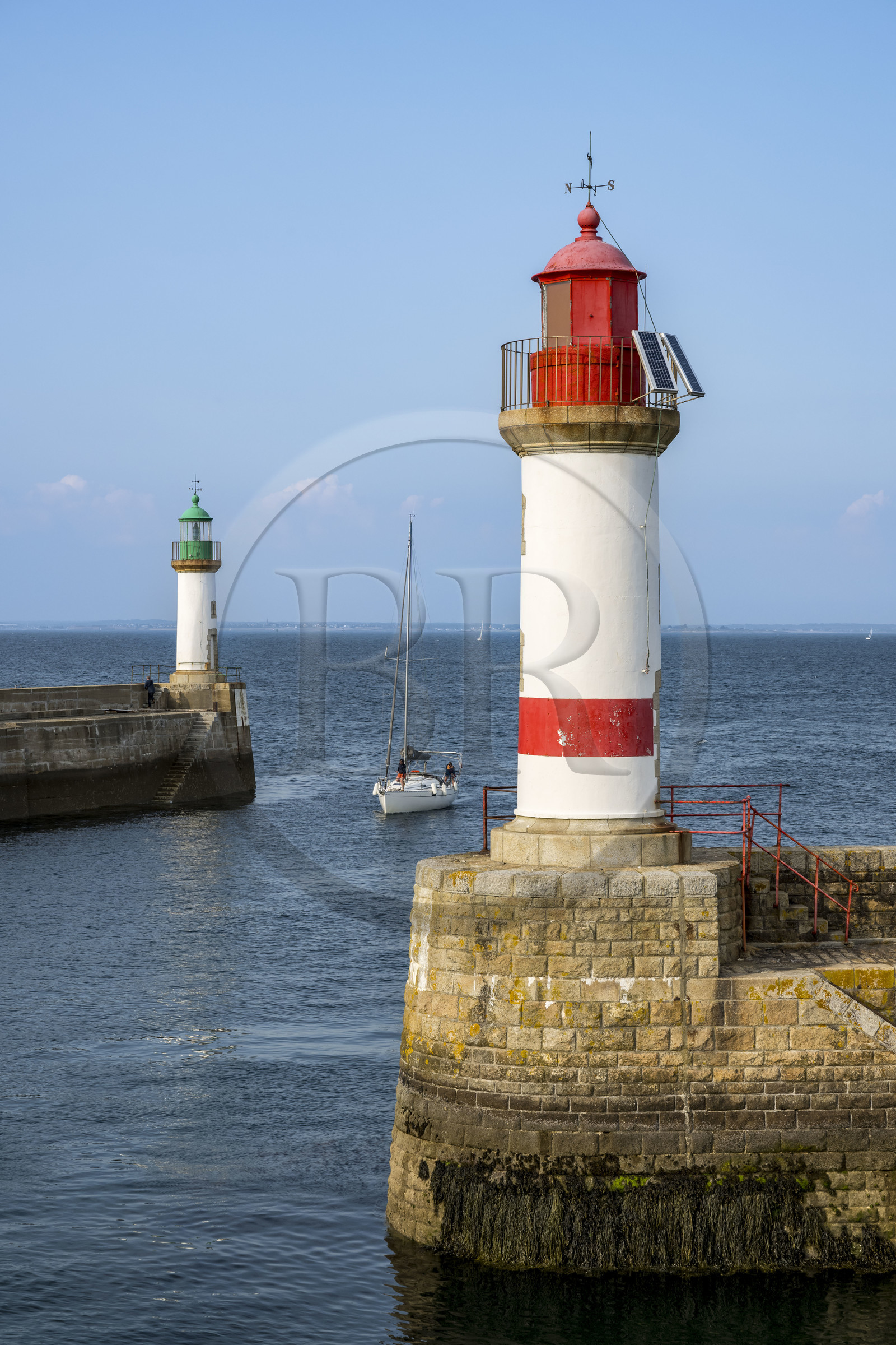 France, Morbihan, Groix Island, Port Tudy, sailboat between the two beacons at the entrance to the port