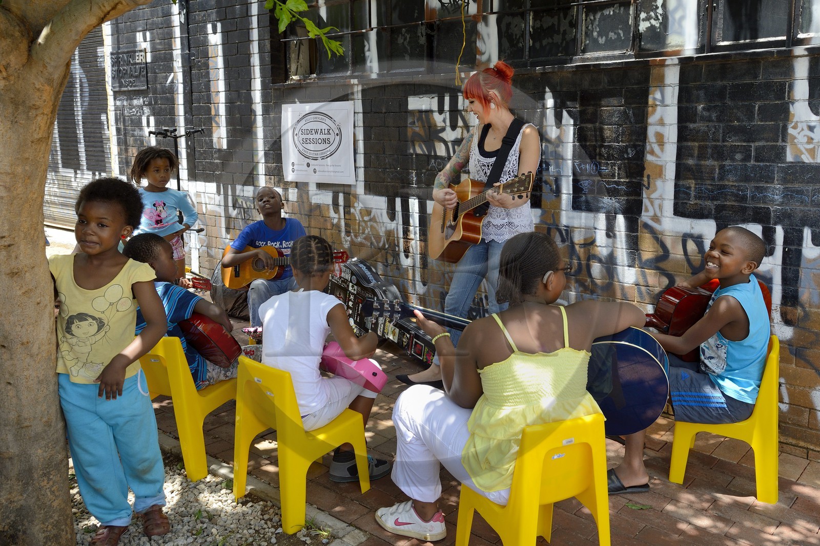 South Africa, Gauteng Province, Johannesburg, CBD (Central Business District), Maboneng district, Sidewalk Sessions in Fox street, Kelly Grevler gives free guitar lessons for young children in the street